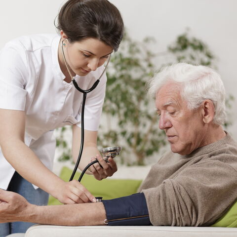 Pflegerin misst den Blutdruck bei einem Herren