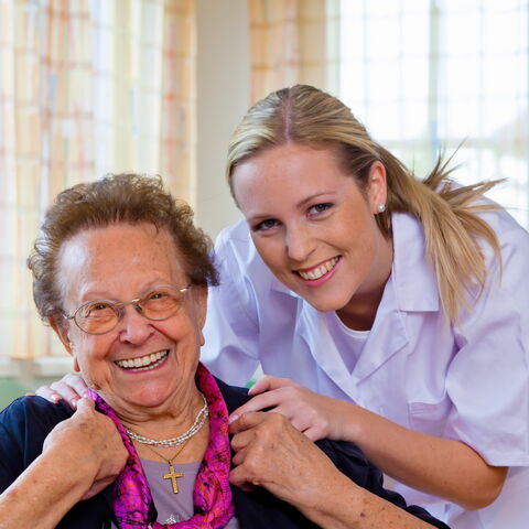 ältere Frau neben jüngerer Pflegerin